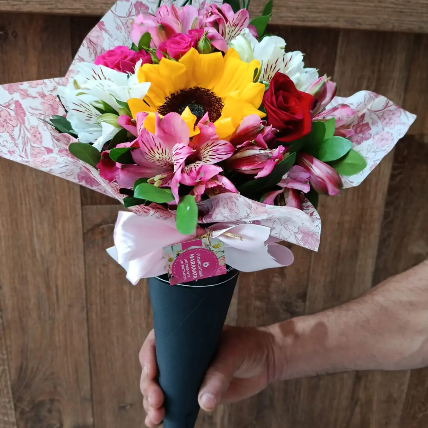 Buquê com girassol central, primaveras e rosa vermelha em cone preto
