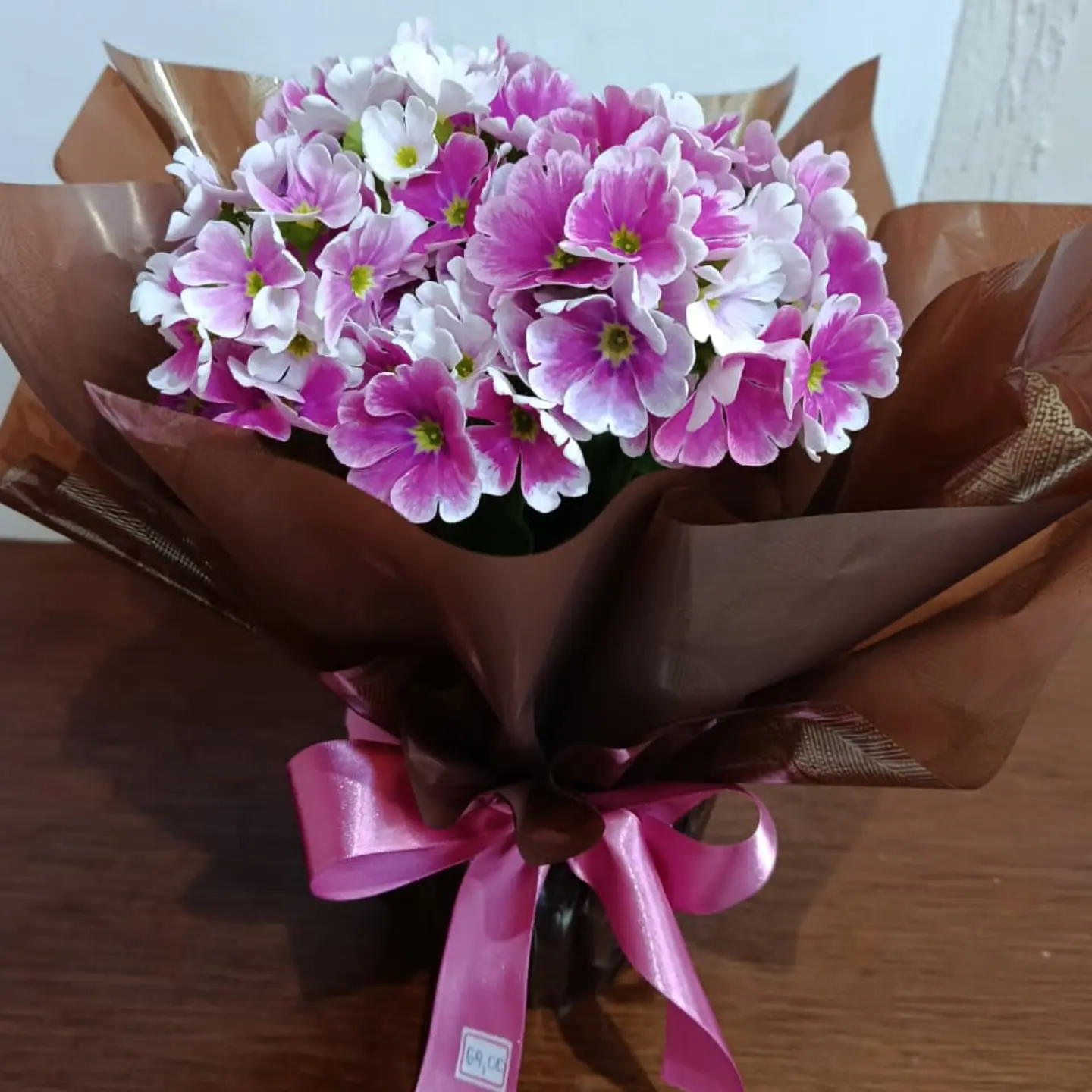 Primaveras rosas e brancas em embalagem marrom
